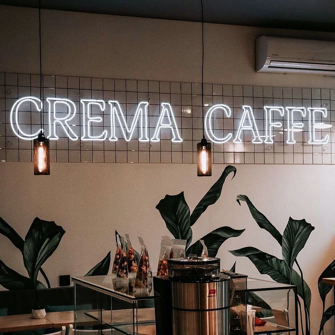 The Perfect Café Setting with a Crema Caffe Neon Sign