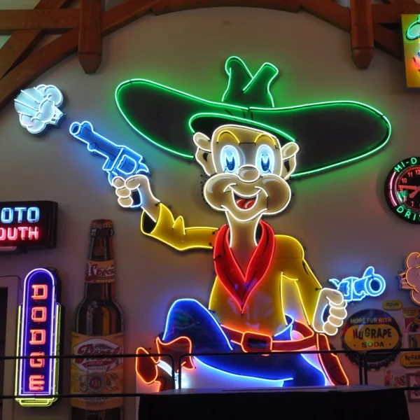 Neon sign showcasing a cartoon cowboy character with a large hat, holding a smoking gun. Surrounding signs include a "Dodge" sign and various vintage advertisements.